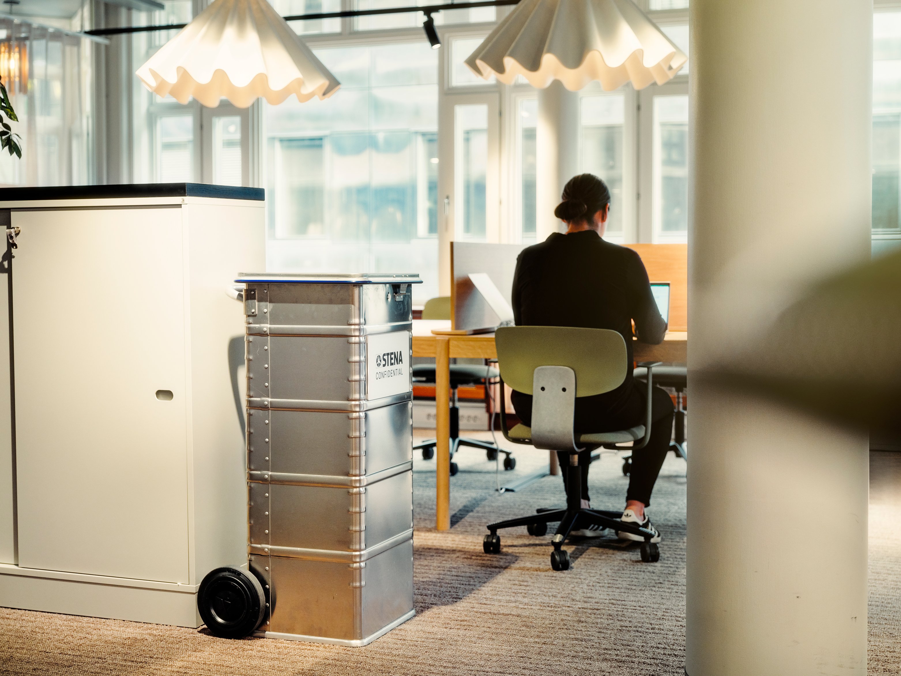 A woman sitting at a desk with her back to the camera.